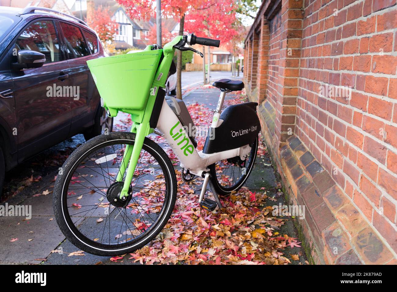 Bicicletta per microtomobilità con cesto verde davanti alla bicicletta, parchi nel marciapiede con albero autunnale colorato lascia Londra Inghilterra Regno Unito Foto Stock