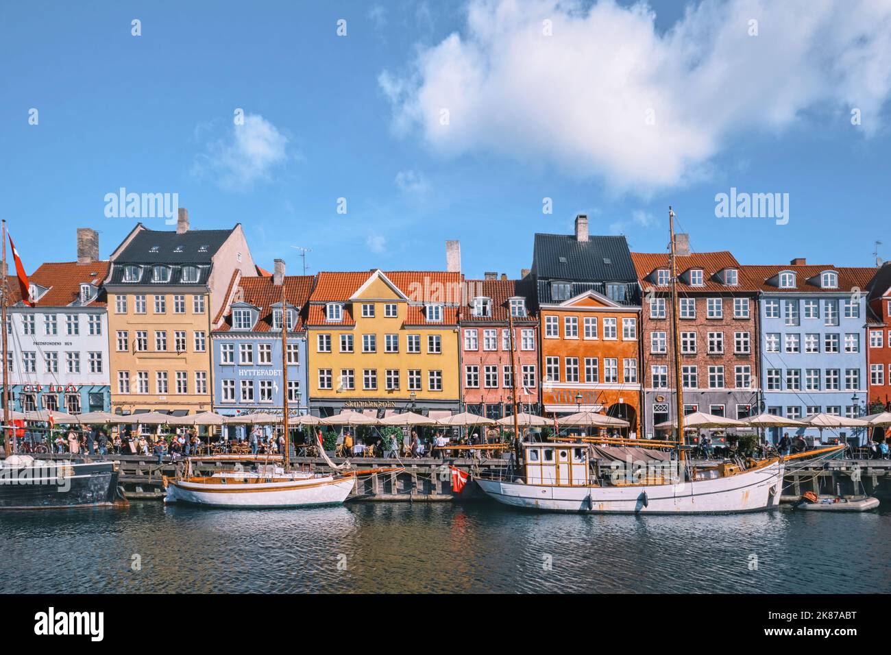 Copenaghen, Danimarca - Settembre 2022: Colorata architettura tradizionale casa e barche sul terrapieno del canale nel porto di Nyhavn Foto Stock