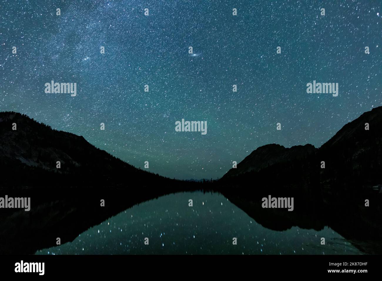 Il lago Toxaway, situato nella Sawtooth Wilderness dell'Idaho, visto in una notte d'estate con molte stelle nel cielo e riflesso nella superficie dell'acqua. Foto Stock