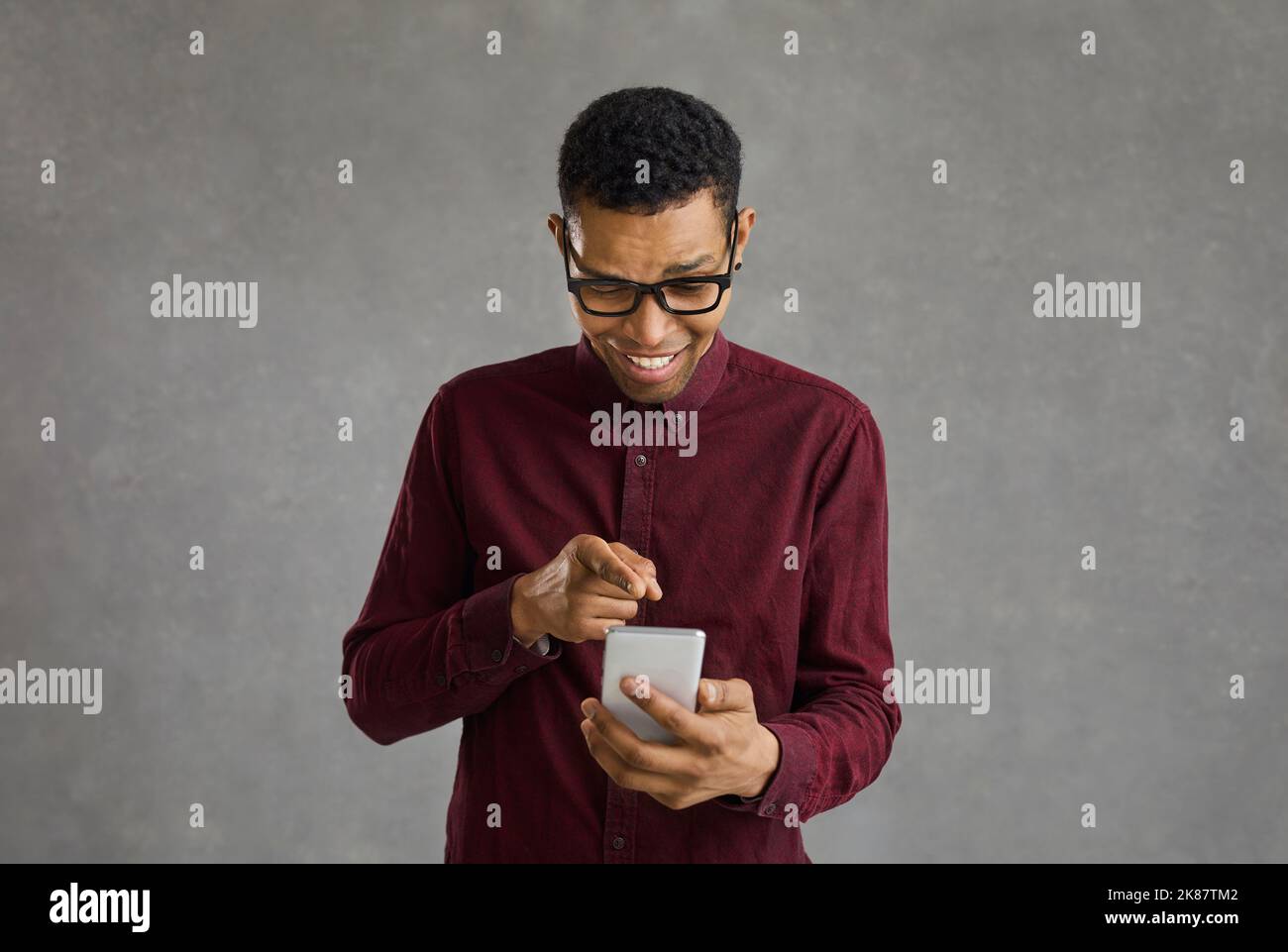 Allegro afro americano ragazzo in stile indossare visualizzare le foto nei social network su cellulare Foto Stock