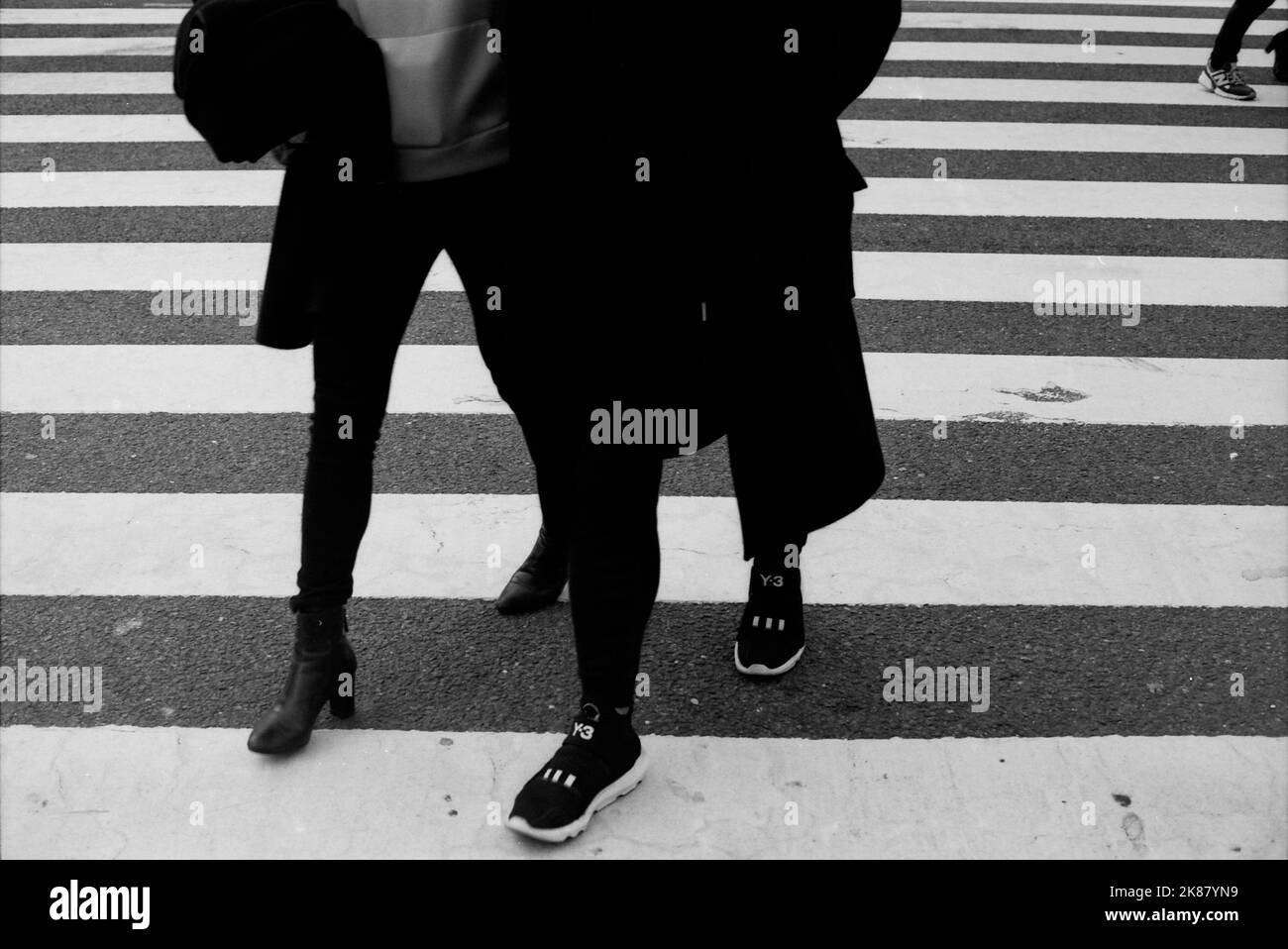 Una scala di grigi di gambe di popoli che attraversano il Shibuya scramble attraversamento a Tokyo Foto Stock