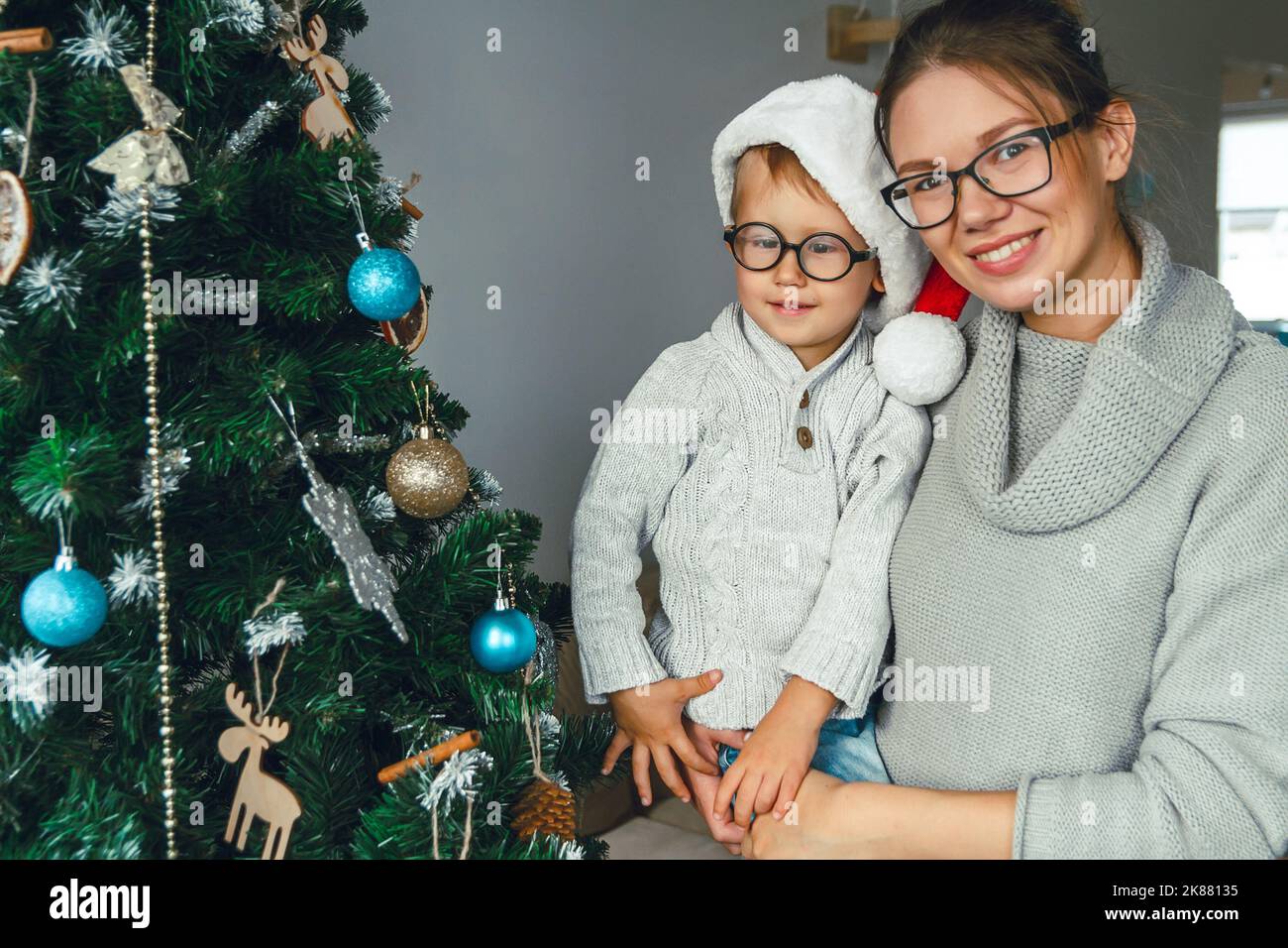 Mamma e bambino decorano insieme l'albero di natale Foto Stock