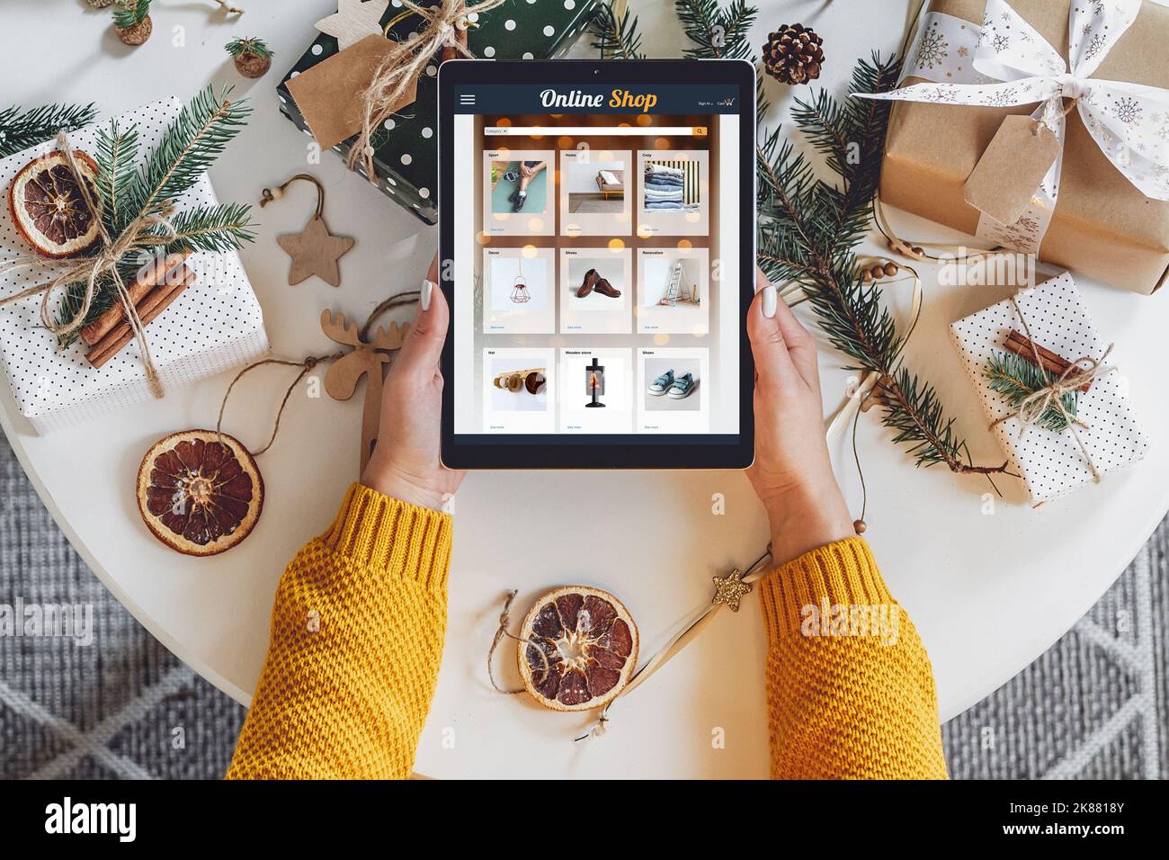 Mani femminili con tablet sul tavolo con decorazioni natalizie fatte a mano Foto Stock