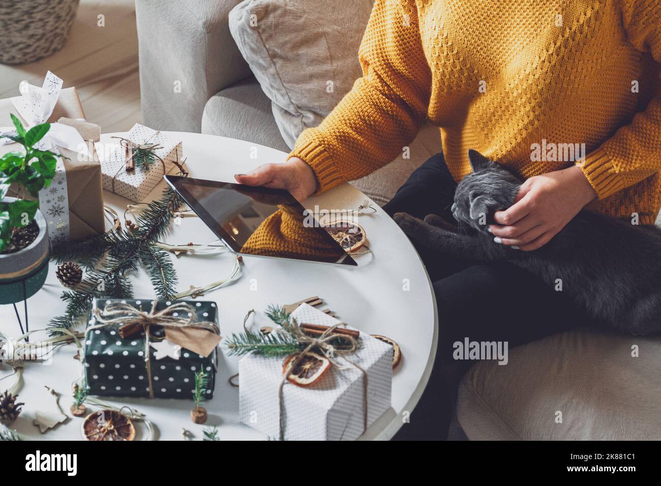 Mani femminili con tablet sul tavolo con decorazioni natalizie fatte a mano Foto Stock