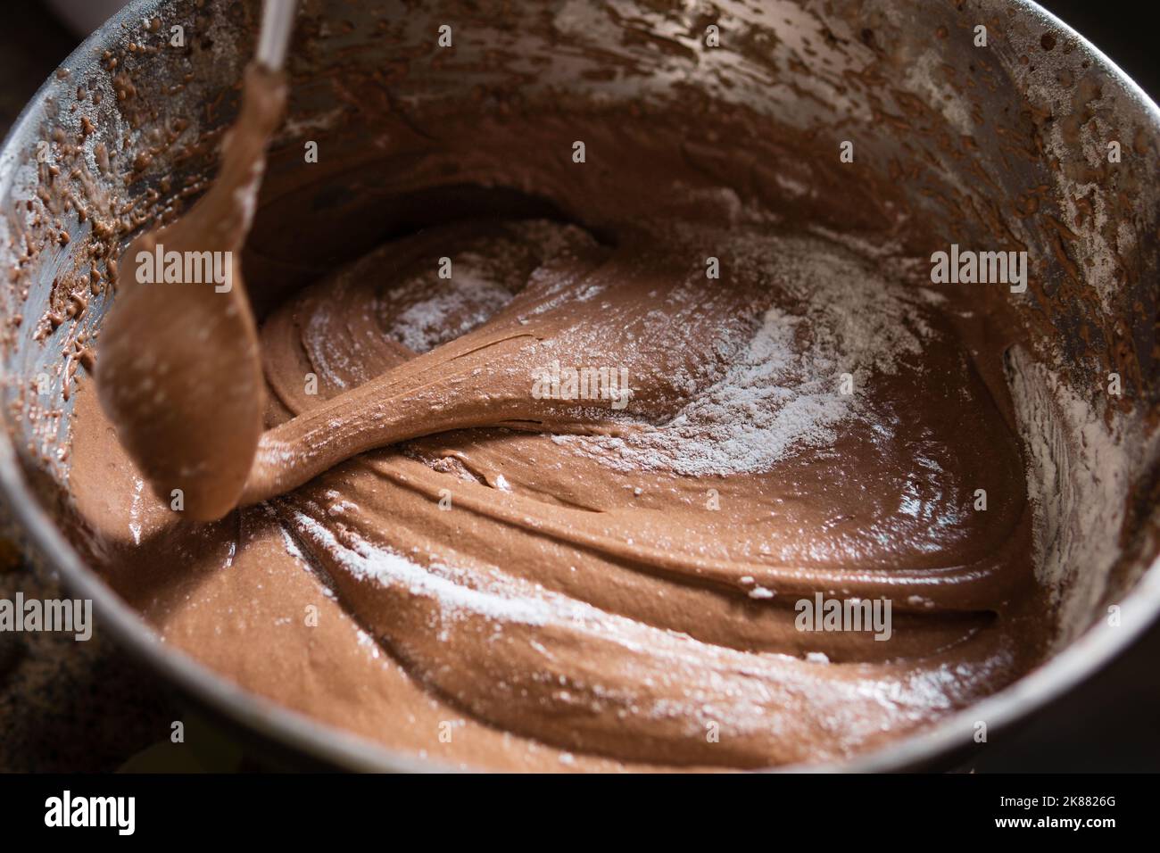 Chiudere un cucchiaio mescolando l'impasto per torte al cioccolato e lo zucchero nel recipiente. Foto Stock