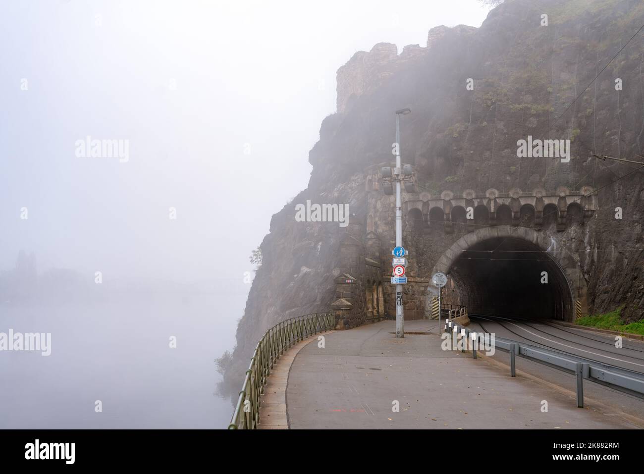 Ingresso a una strada, tram e tunnel pedonale sotto la roccia di Vyšerhad a Praga. Misty mattina d'autunno, con nebbia sopra il fiume Moldava. Foto Stock