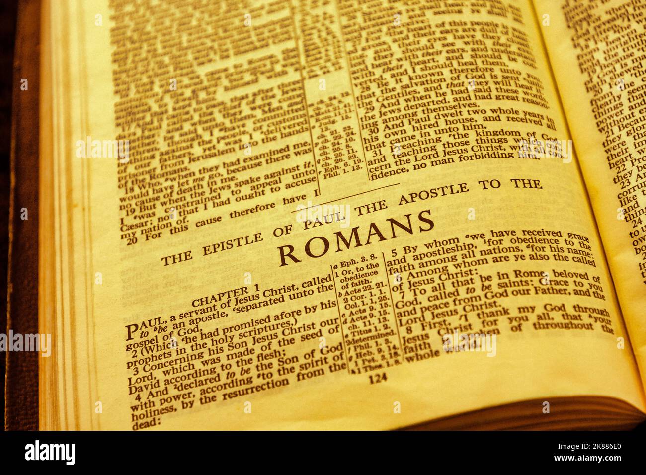Primo piano dell'antica pagina della Sacra Bibbia, profondità di campo poco profonda con particolare attenzione al titolo del capitolo, Romani Foto Stock