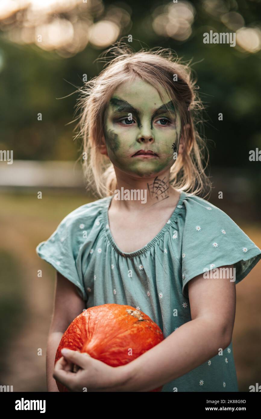 Ragazza piccola con trucco strega Halloween partito con una zucca Foto Stock