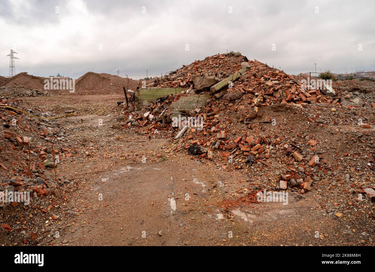 Pile di macerie di mattoni, pietra e cemento. Resti dell'edificio industriale distrutto sotto il cielo color piombo Foto Stock