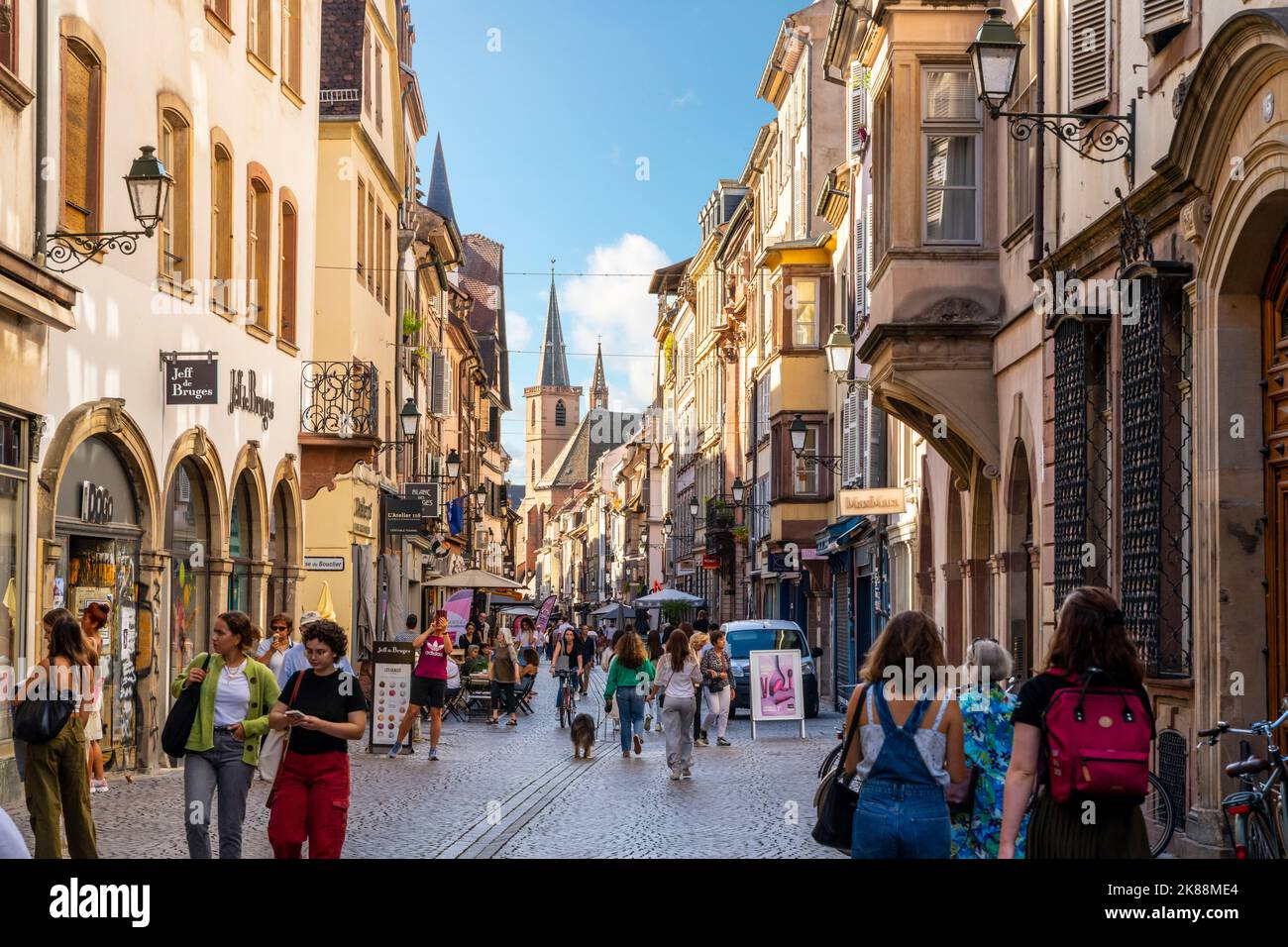 I turisti e i francesi locali godono i negozi e caffè su una strada di mezzo legno edifici nella medievale Strasburgo Francia. Foto Stock