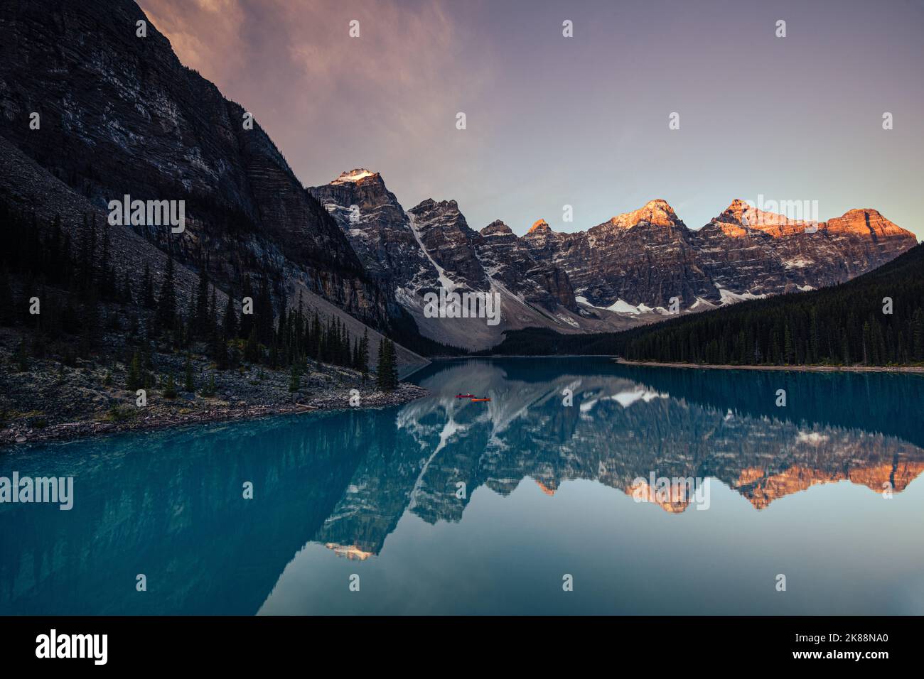 Moraine Lake, Canadian Rockies, Canada, all'alba con le montagne che si riflettono nell'acqua e 2 canoe nel lago Foto Stock
