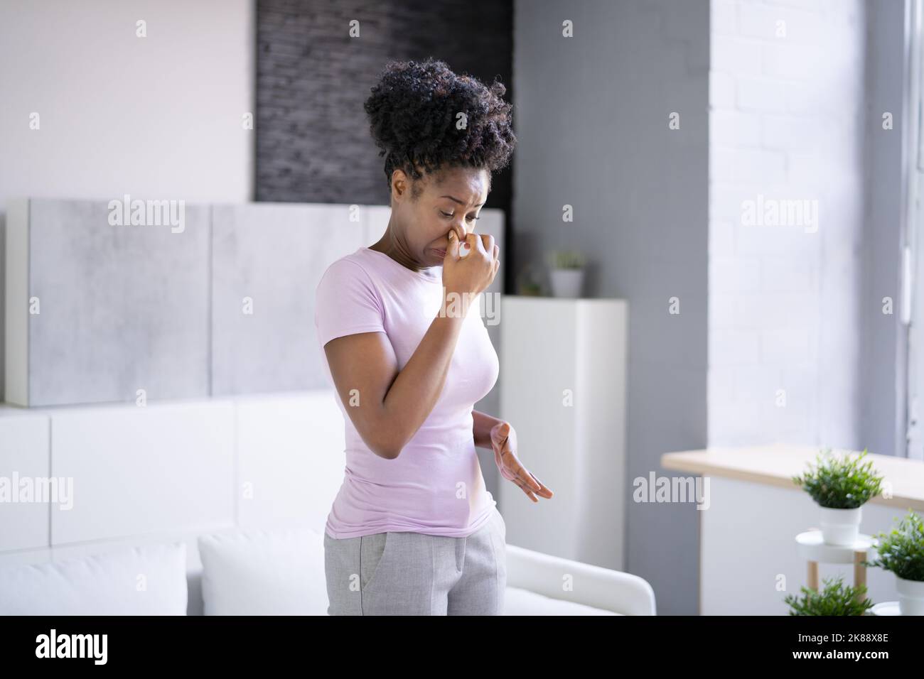 Donna africana che sente cattivo odore di aria o Odor in casa Foto Stock