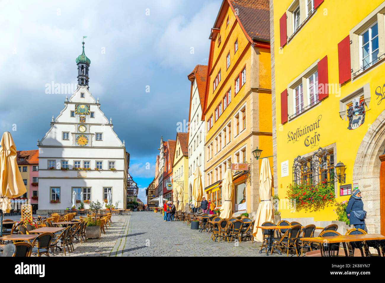 La Torre dell'Orologio di Ratstrinkstube, con negozi colorati e caffetterie sul marciapiede, si trova nella storica piazza del Municipio di Rothenburg ob der Tauber, Germania. Foto Stock