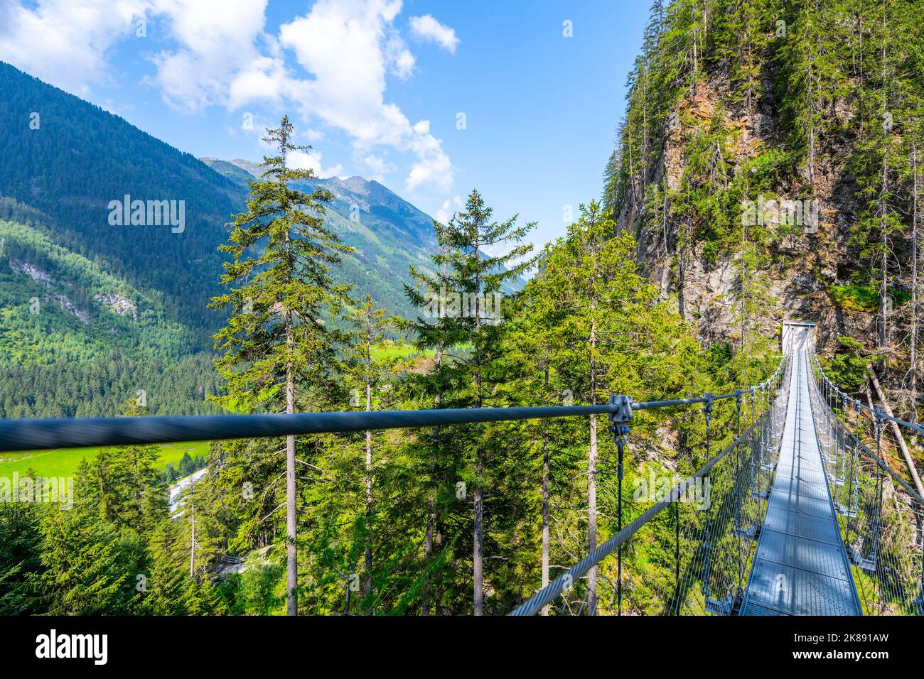 Semplice ponte sospeso sulla valle di montagna Foto Stock