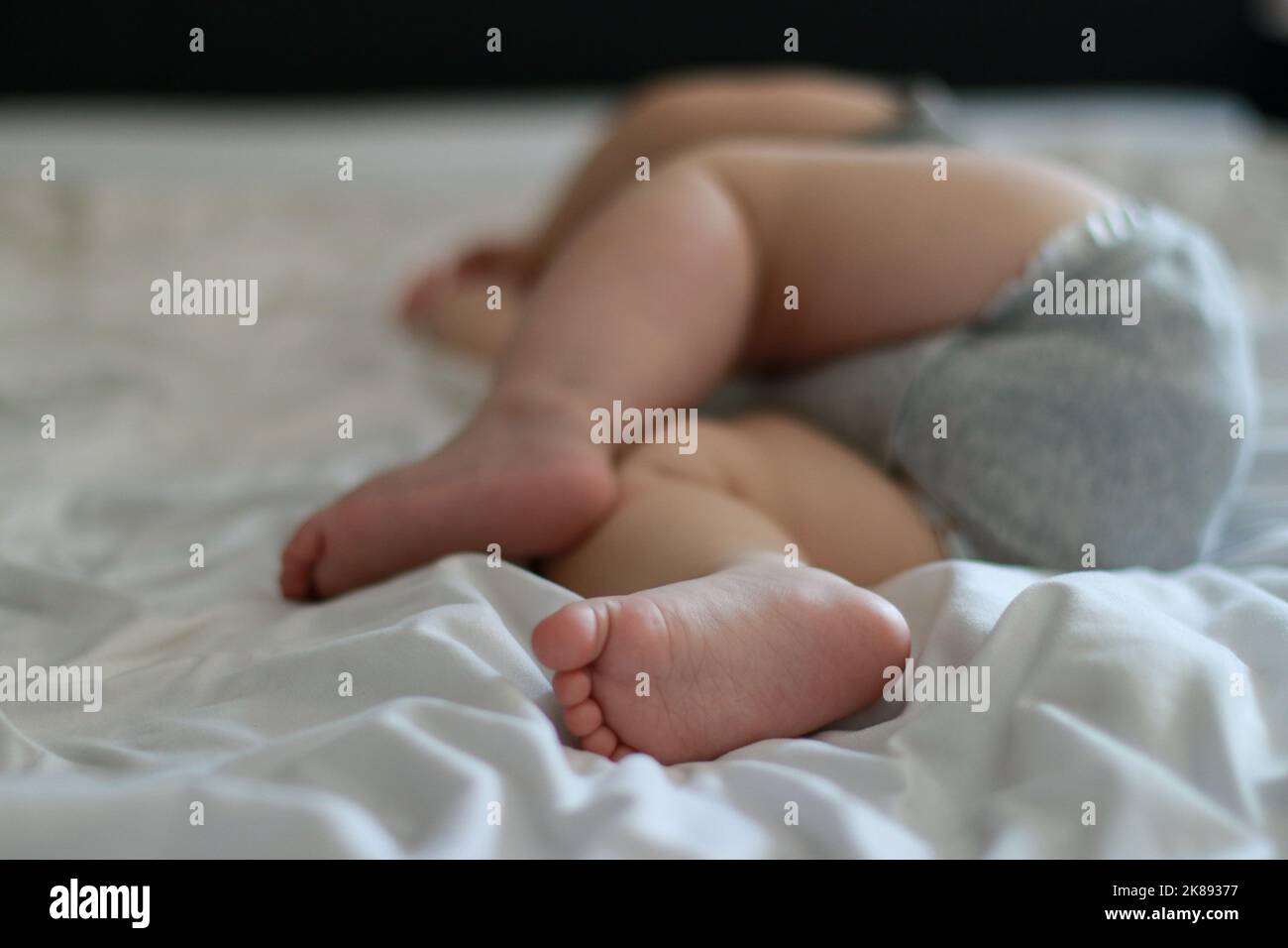 primo piano del bambino addormentato di 9 mesi, letto con lenzuola bianche Foto Stock