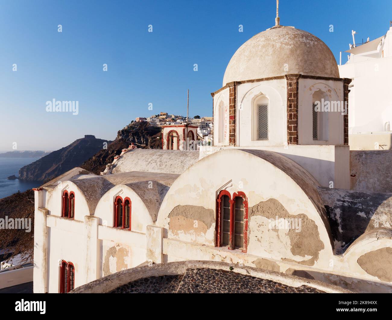 San Giovanni la chiesa teologica nella città di Fira, isola greca delle Cicladi di Santorini nel Mar Egeo. Skaros Rock a sinistra Foto Stock