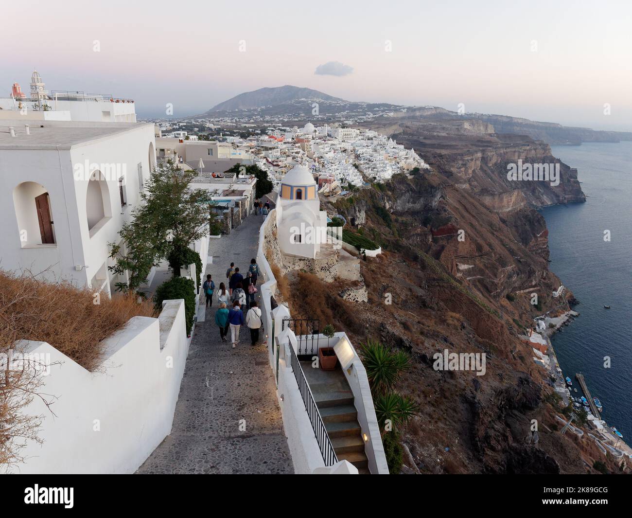 Città di Fira al tramonto da un sentiero costiero con la costa della Caldera. Isole Cicladi greche di Santorini nel Mar Egeo Foto Stock