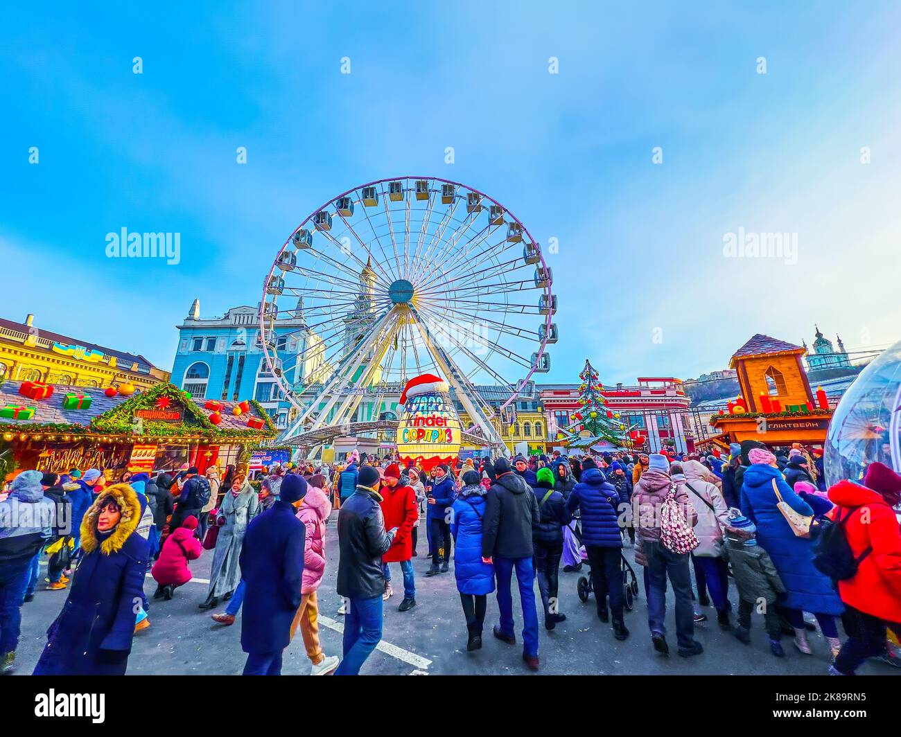 KIEV, UCRAINA - 2 GENNAIO 2022: Mercato di Natale affollato e occupato sulla piazza dei contratti con l'albero di Natale, ruota ferris e bancarelle del mercato, su Foto Stock