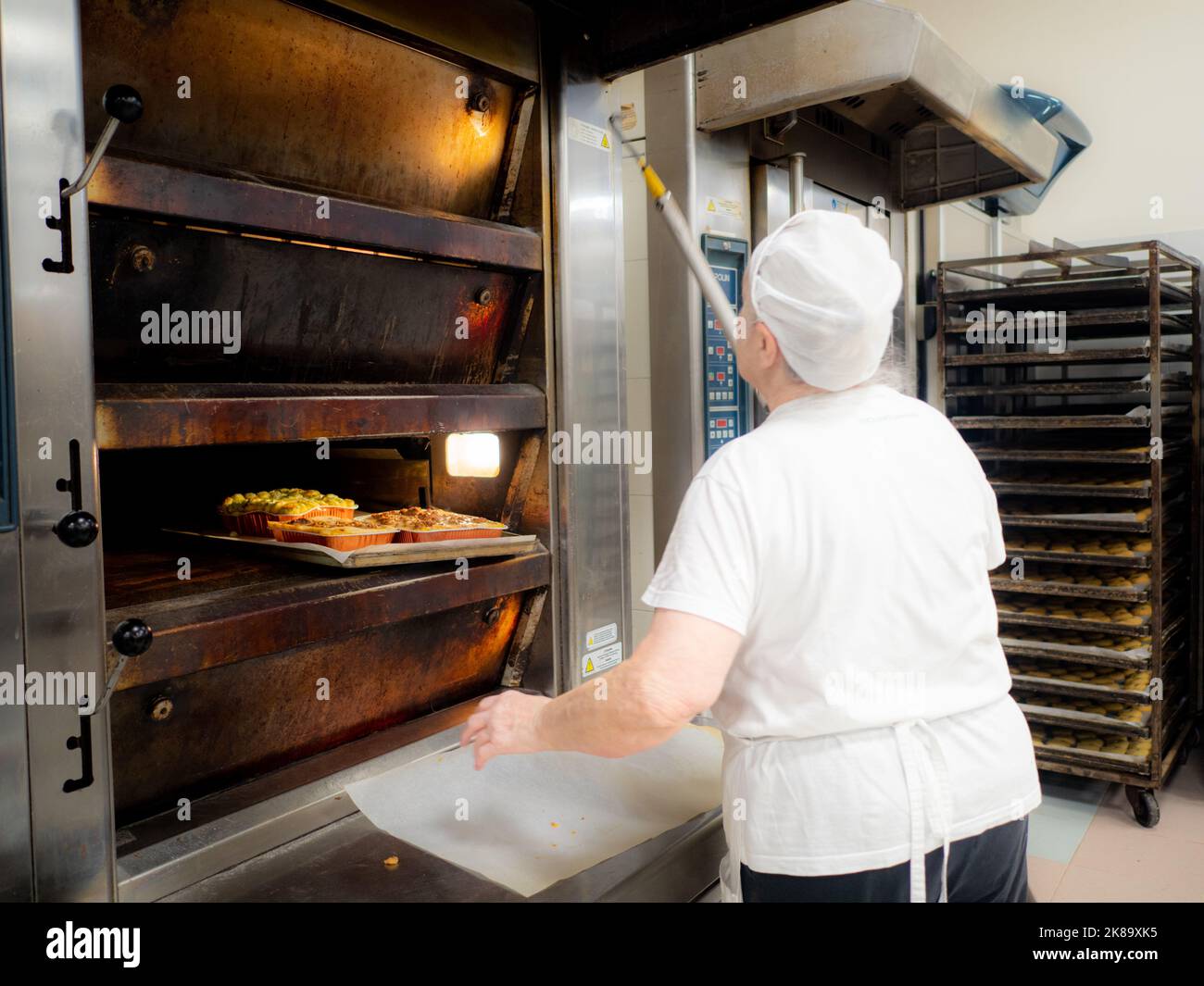 signora anziana al lavoro nel grande ristorante panetteria Foto Stock