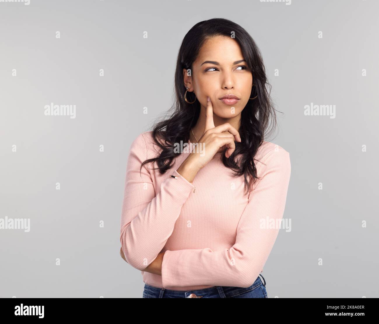 Ho odore qualcosa di pesce... una bella giovane donna che guarda pensierosa mentre si trova su uno sfondo grigio. Foto Stock