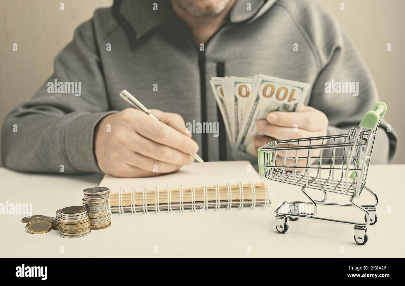 L'uomo divide i soldi per i bisogni della famiglia. Bilancio familiare, finanze di pianificazione. Pagamento di fatture, tasse e spese di vita. Inflazione e risparmio. Alloggio totale Foto Stock