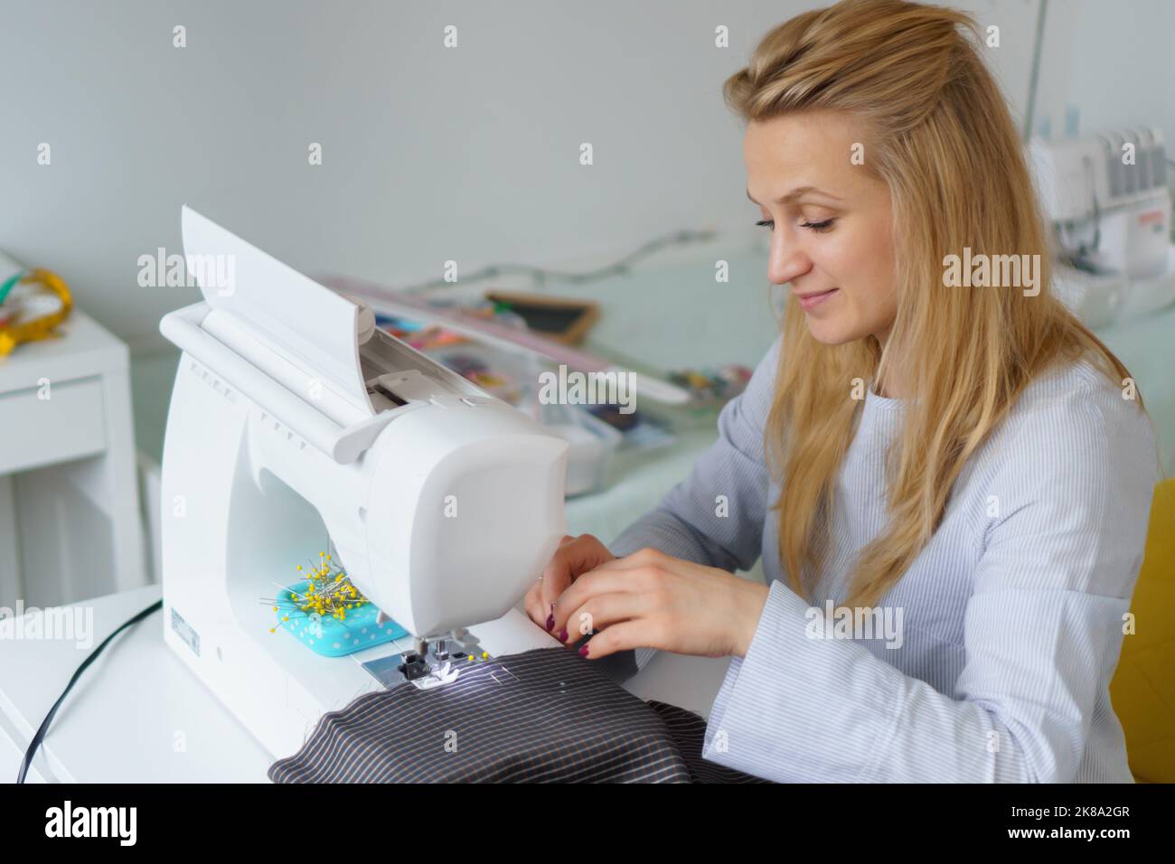 La donna di seamstress lavora sulla macchina da cucire. Le mani del dressaker lavorano alla fabbrica di cucire Foto Stock