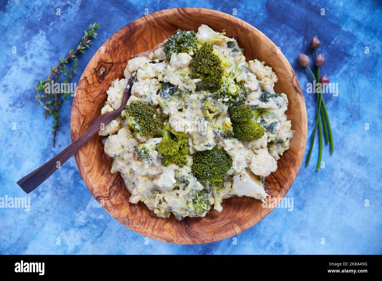 La vostra dieta è un conto bancario, le buone scelte alimentari sono buoni investimenti. Colpo di testa di cavolfiore e broccoli in una ciotola di legno su un blu Foto Stock