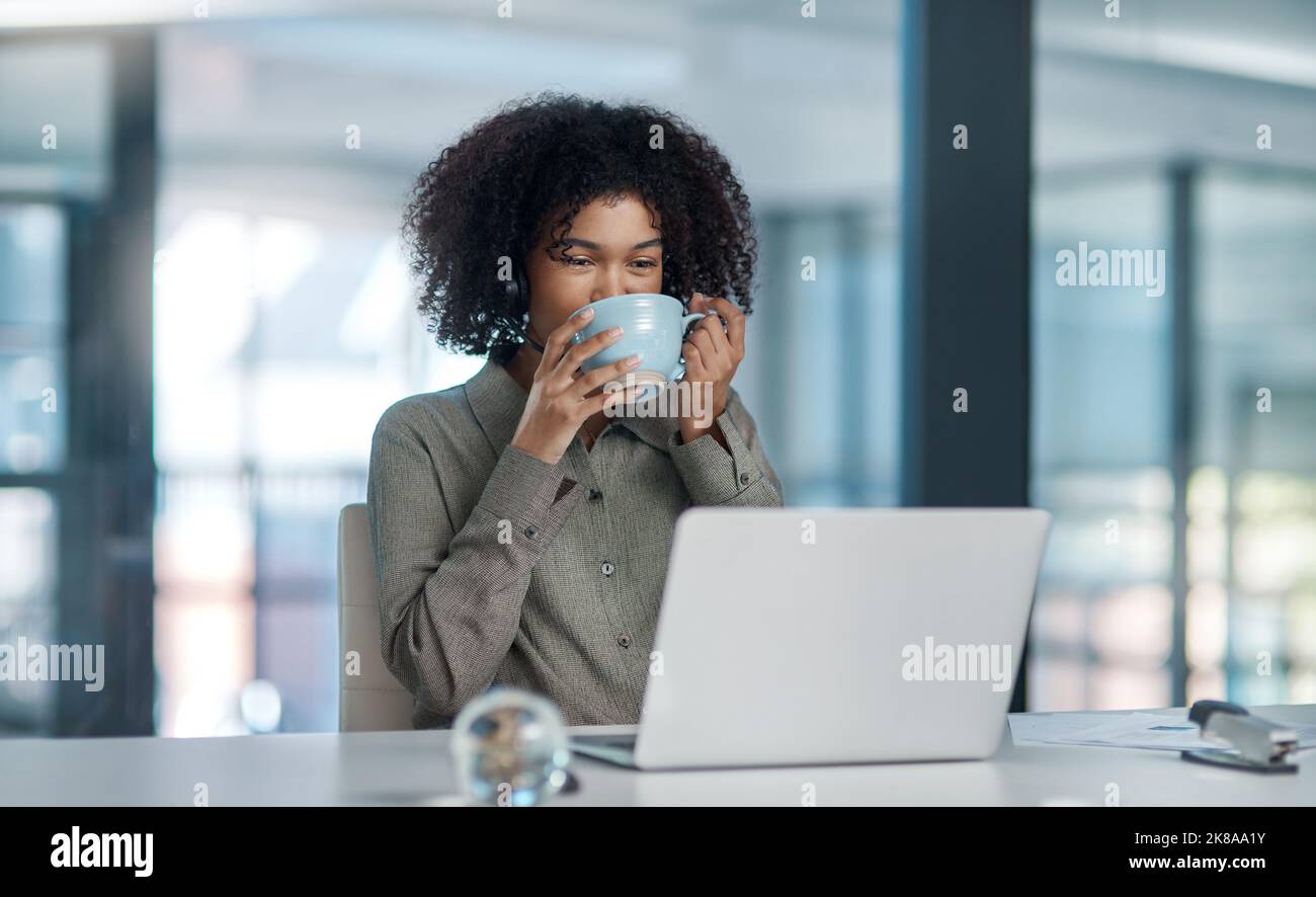 L'umanità corre sul caffè. Una giovane agente femminile che lavora in un call center che si prende un momento per gustare un sorso di caffè. Foto Stock