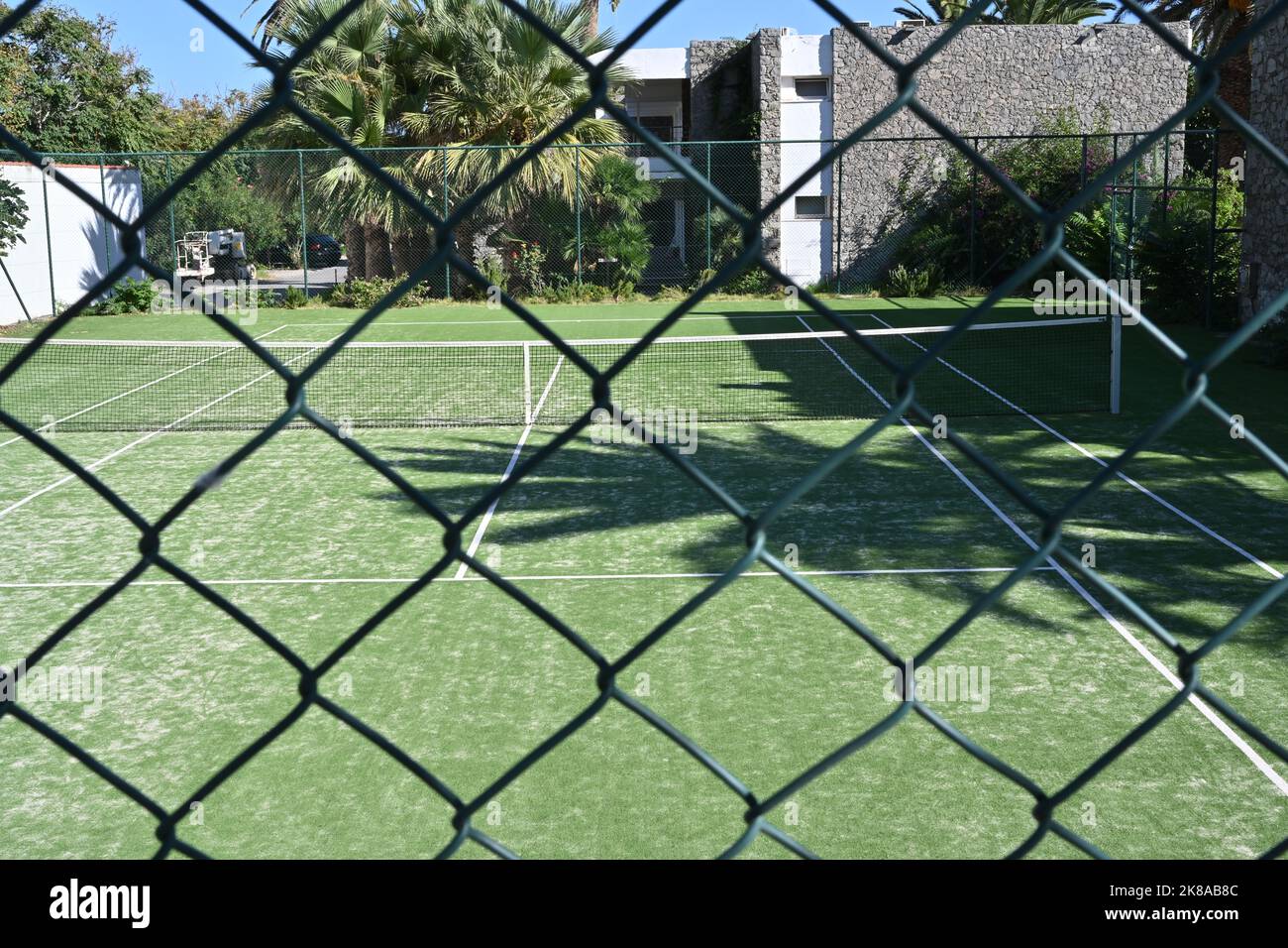 Vista sul campo da tennis in erba o prato da dietro la recinzione metallica. Foto Stock