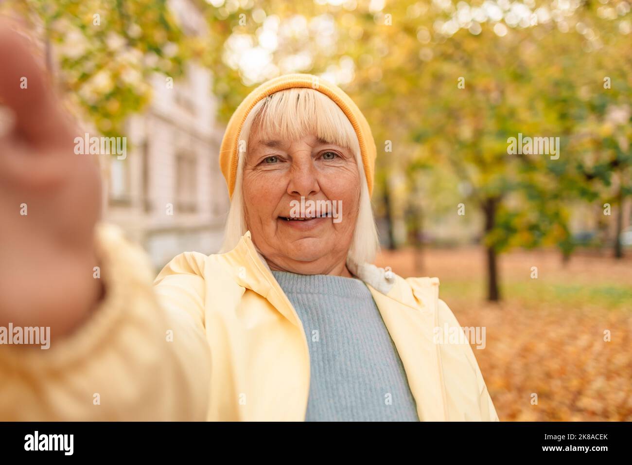 Donna anziana felice che prende selfie al parco autunnale Foto Stock