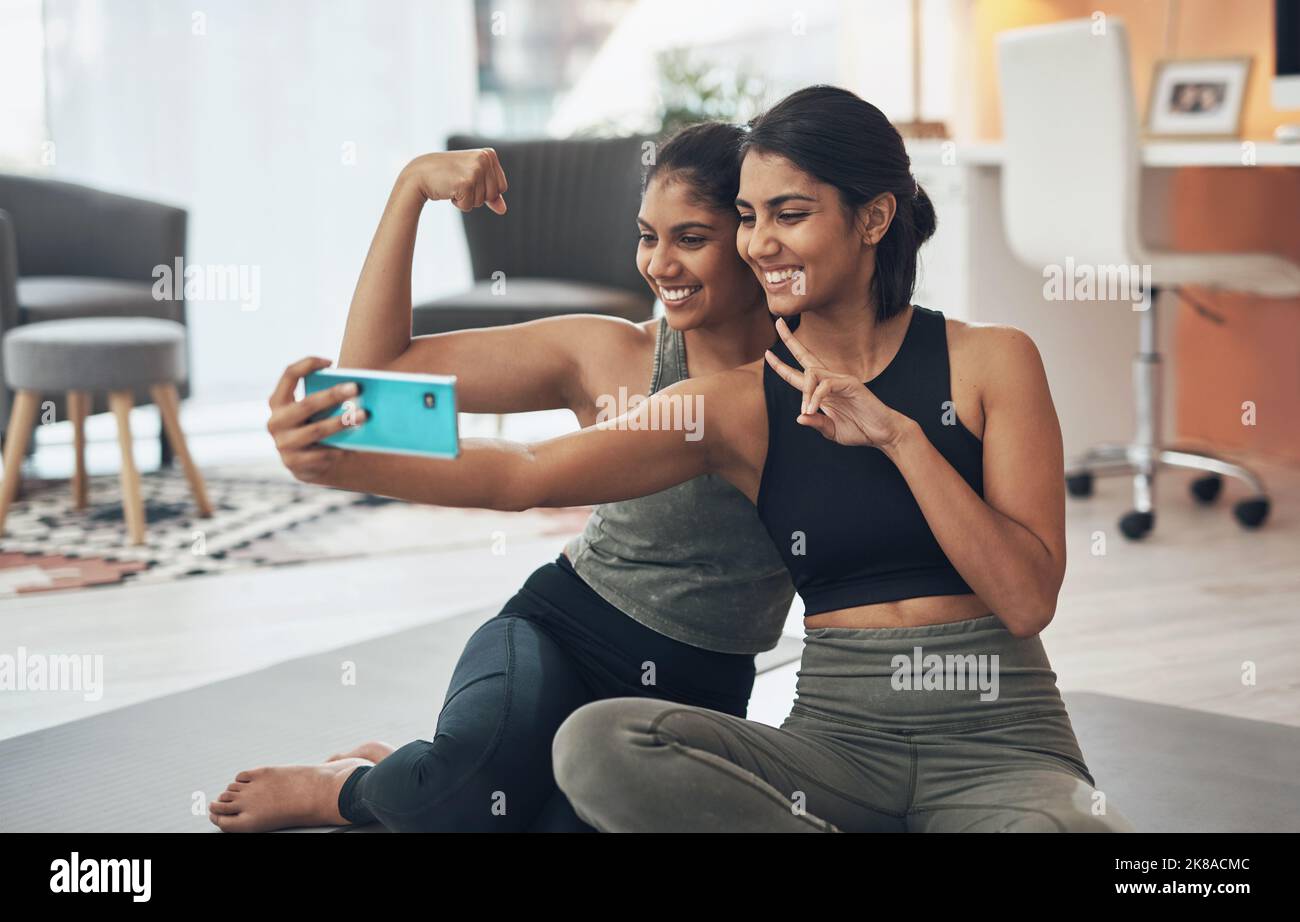 Sono sempre state in vena di un selfie dopo un allenamento. Due giovani donne che prendevano un selfie mentre erano seduti a casa in abiti da ginnastica. Foto Stock