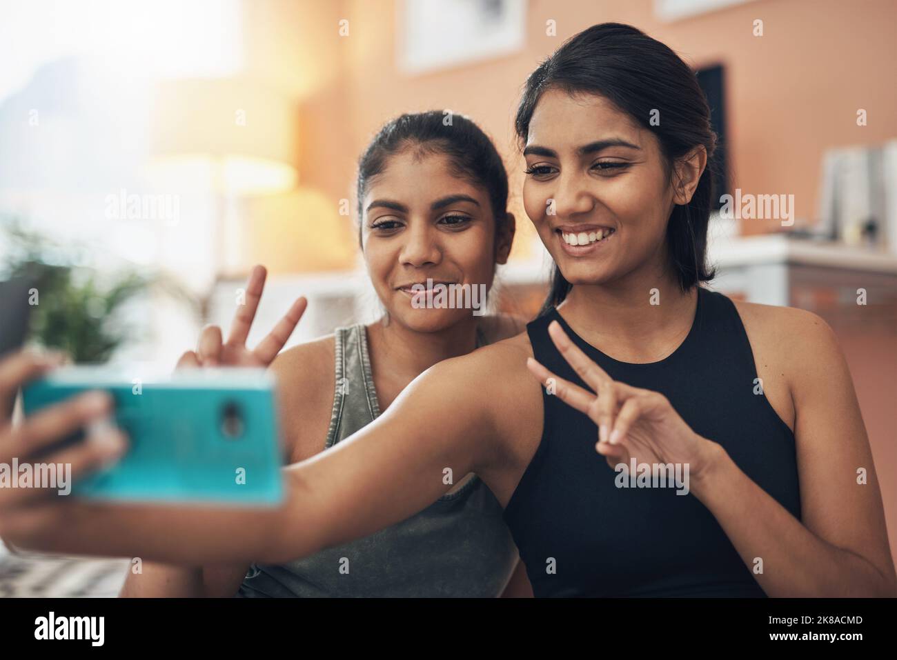 Sempre più sane e felici insieme. Due giovani donne che prendono un selfie mentre si siedono a casa in abiti da ginnastica. Foto Stock