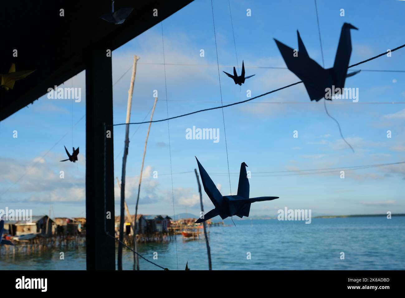 La silhouette di gru di carta appesa al di fuori di una scuola villaggio bajau. Foto Stock