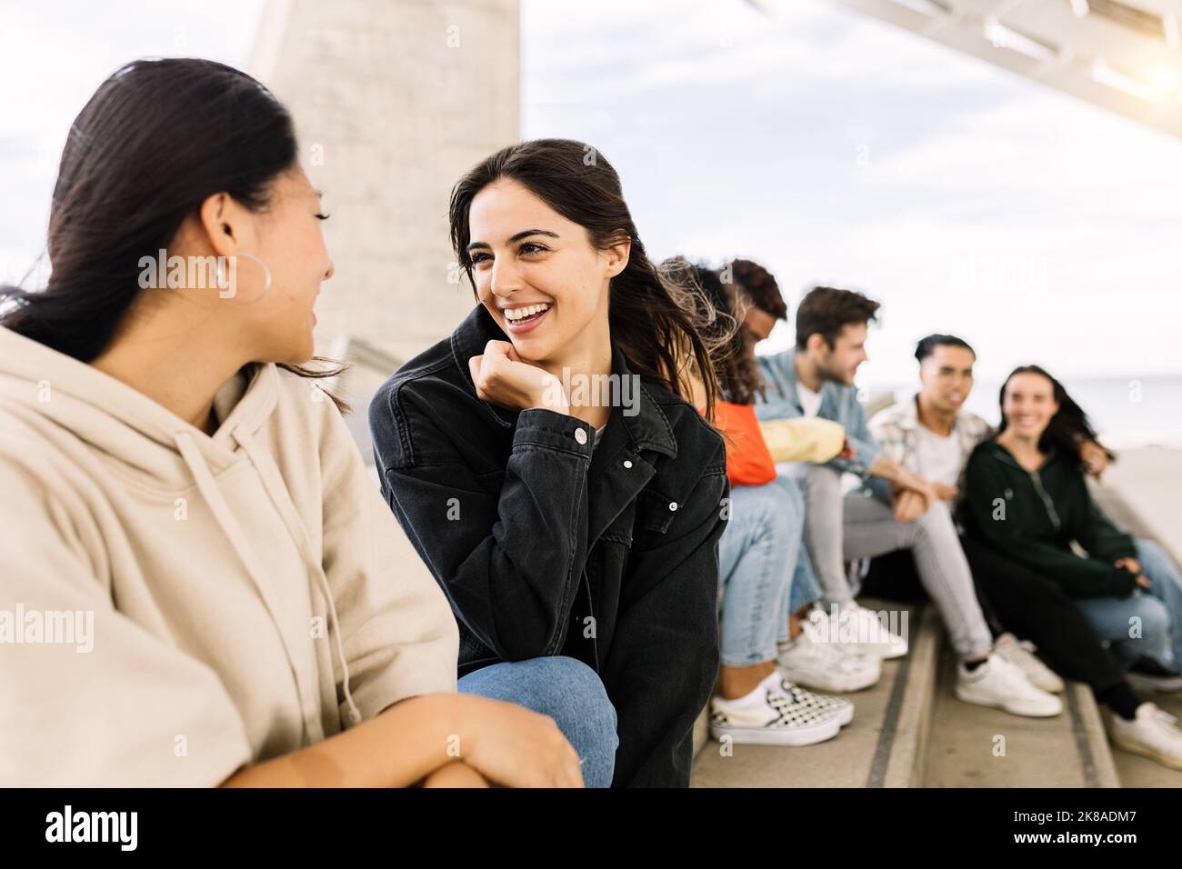 Felice giovane gruppo di amici multirazziali che si appendono insieme all'aperto Foto Stock