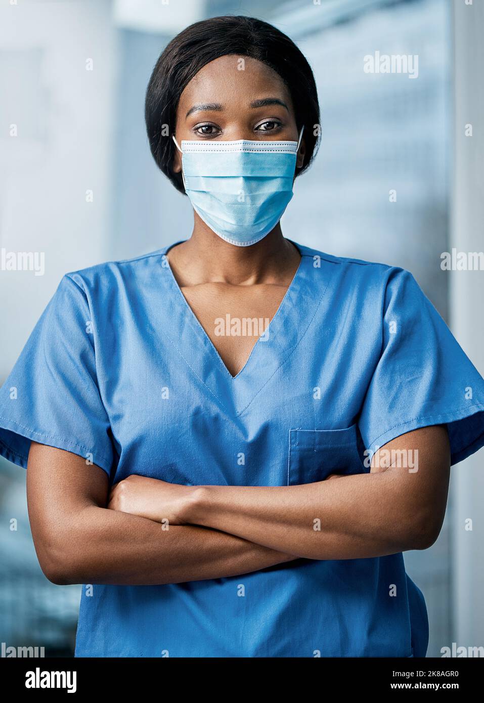 In piedi pronti per affrontare qualsiasi emergenza. Ritratto di un medico che indossa una maschera facciale in un ospedale. Foto Stock