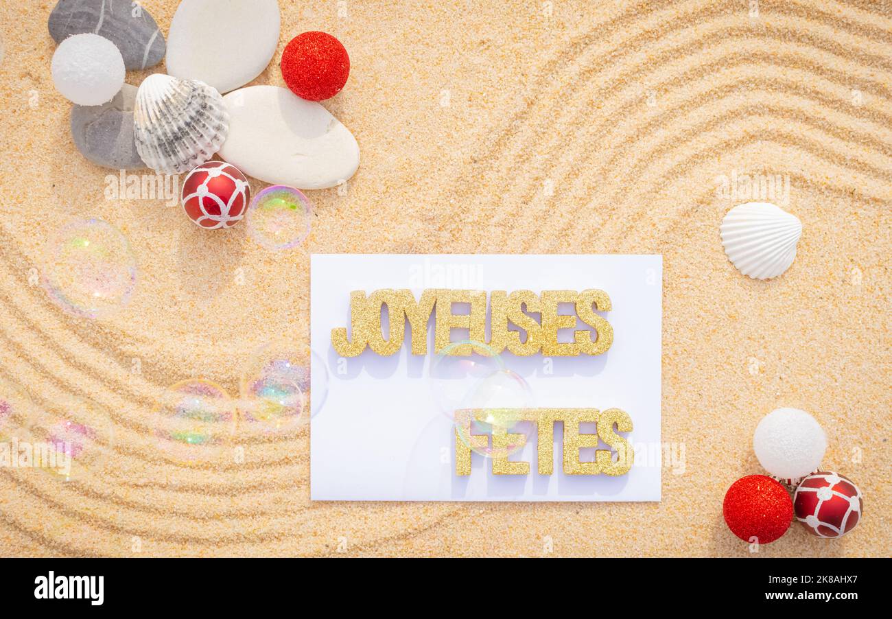 Sfondo sabbia di mare, sabbia fine spiaggia con ciottoli e baubles di Natale. Messaggio buone feste. Foto Stock