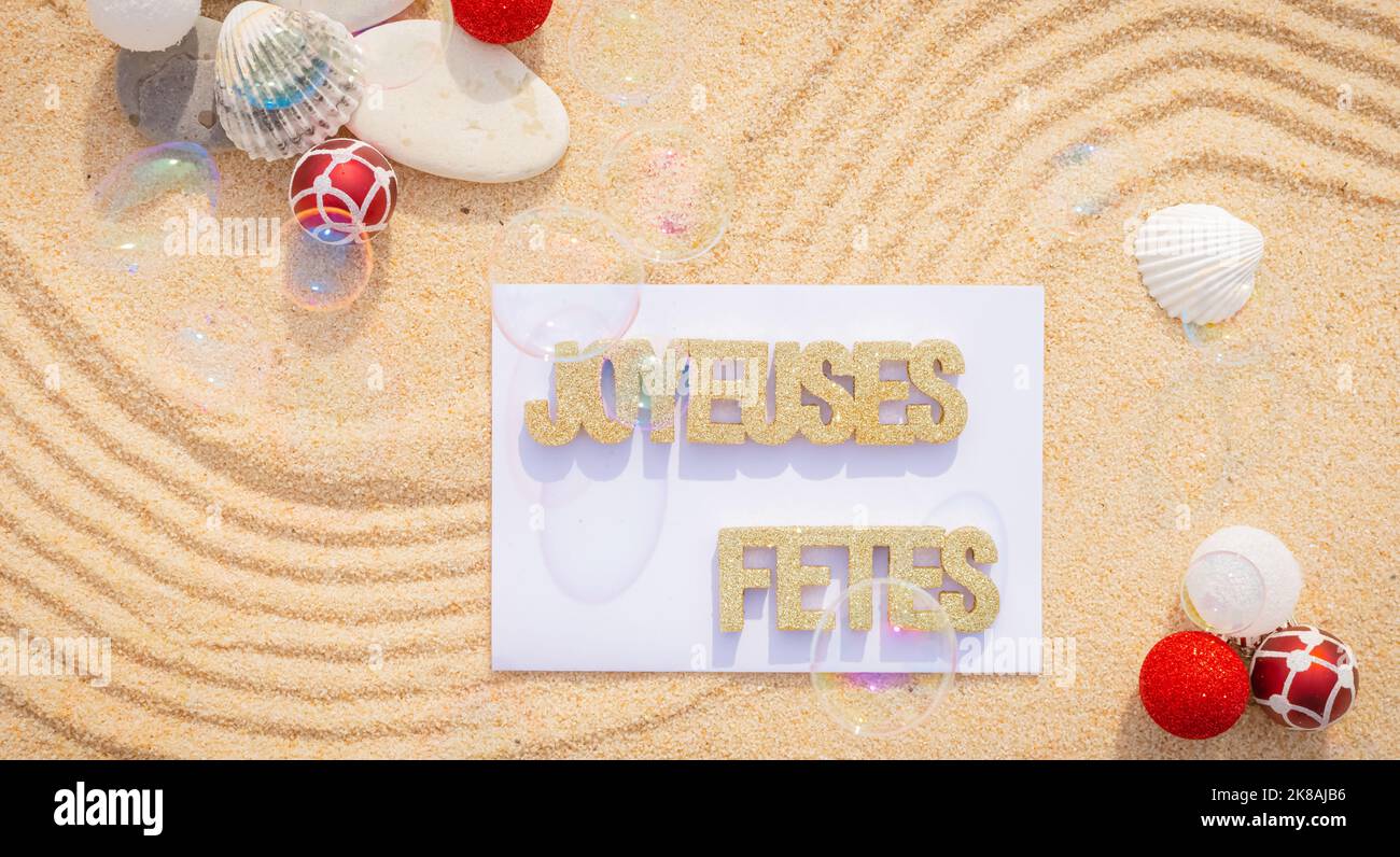 Sfondo sabbia di mare, sabbia fine spiaggia con ciottoli e baubles di Natale. Messaggio buone feste. Foto Stock