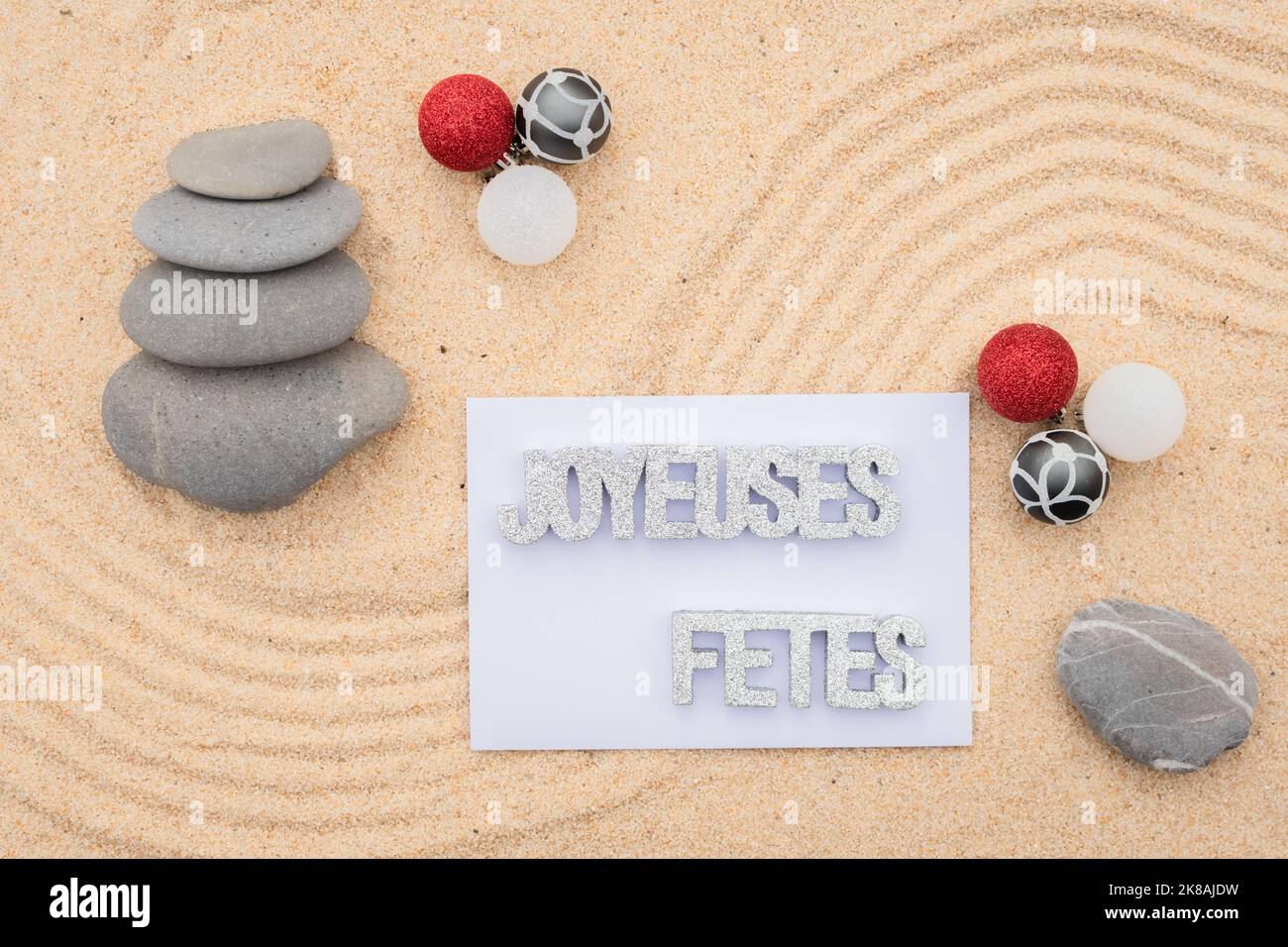 Sfondo sabbia di mare, sabbia fine spiaggia con ciottoli e baubles di Natale. Messaggio buone feste. Foto Stock