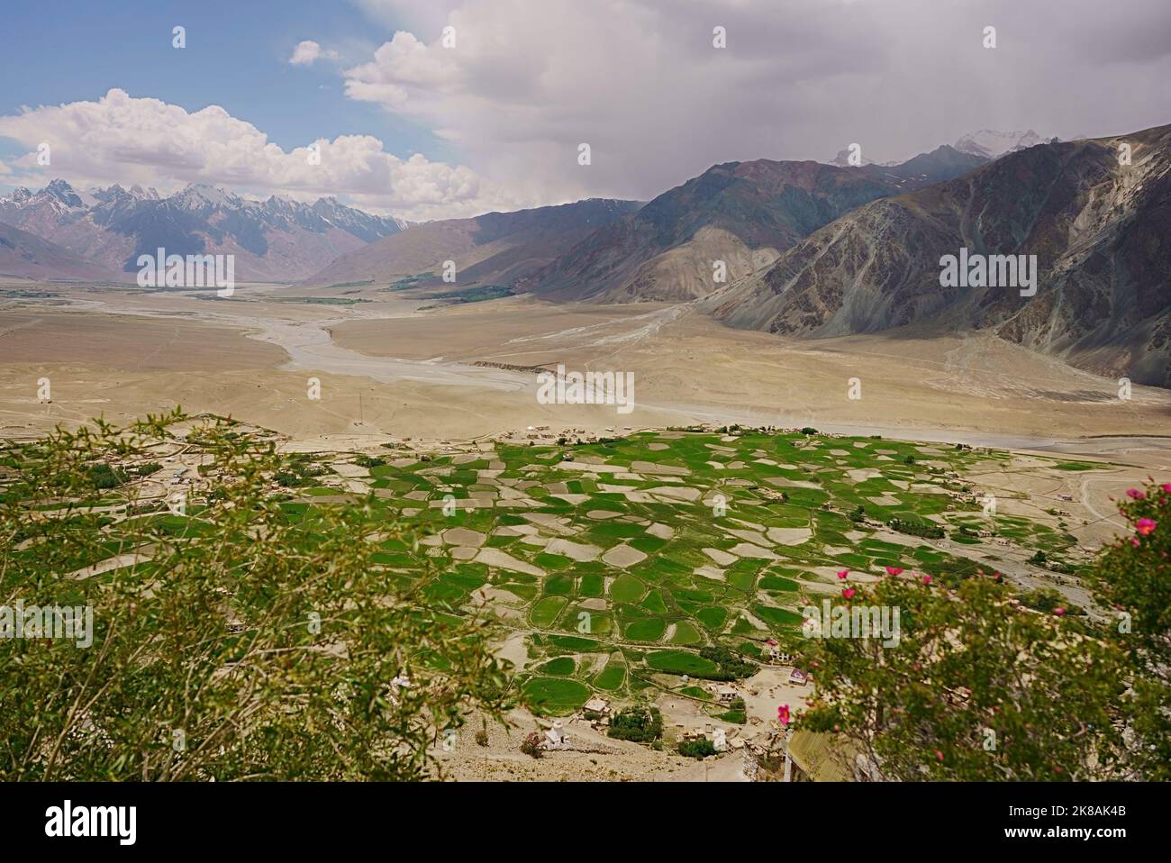 Veduta aerea ampia di verde contrastante campi paesaggio fattorie in arido deserto freddo arido montagne aride esposte roccia colorata in una valle del fiume Foto Stock