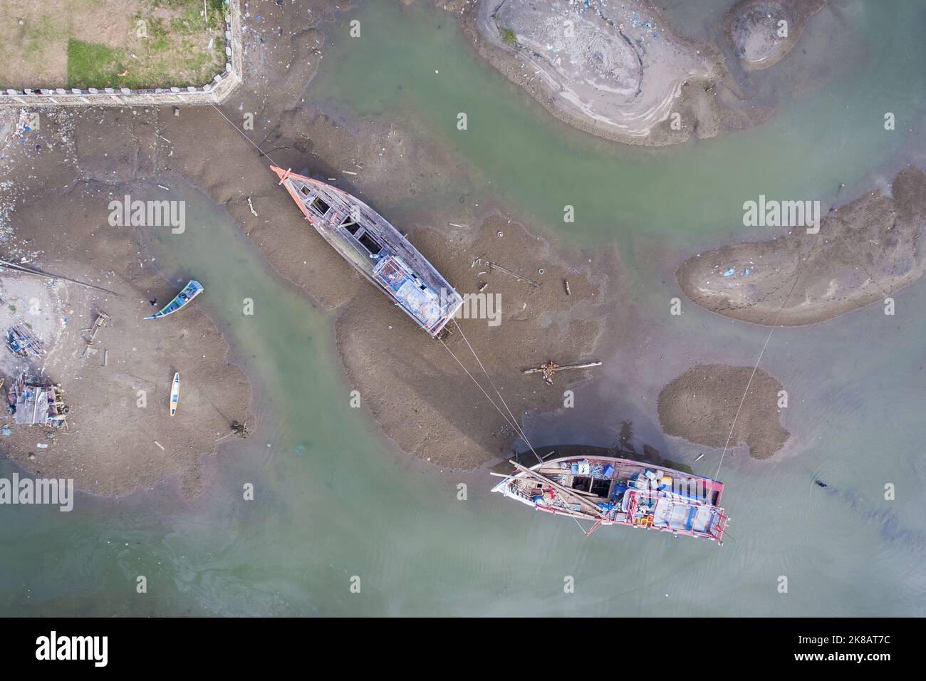 Aceh, Indonesia. Ottobre 22, 2022. Due barche danneggiate necessitano di riparazione e sono ormeggiate nella sabbia con corde interbloccanti. Le riparazioni sono state effettuate in un cantiere navale particolare per le navi da pesca nella zona dell'estuario del villaggio di Pusong, Lhokseumawe City. Foto Stock