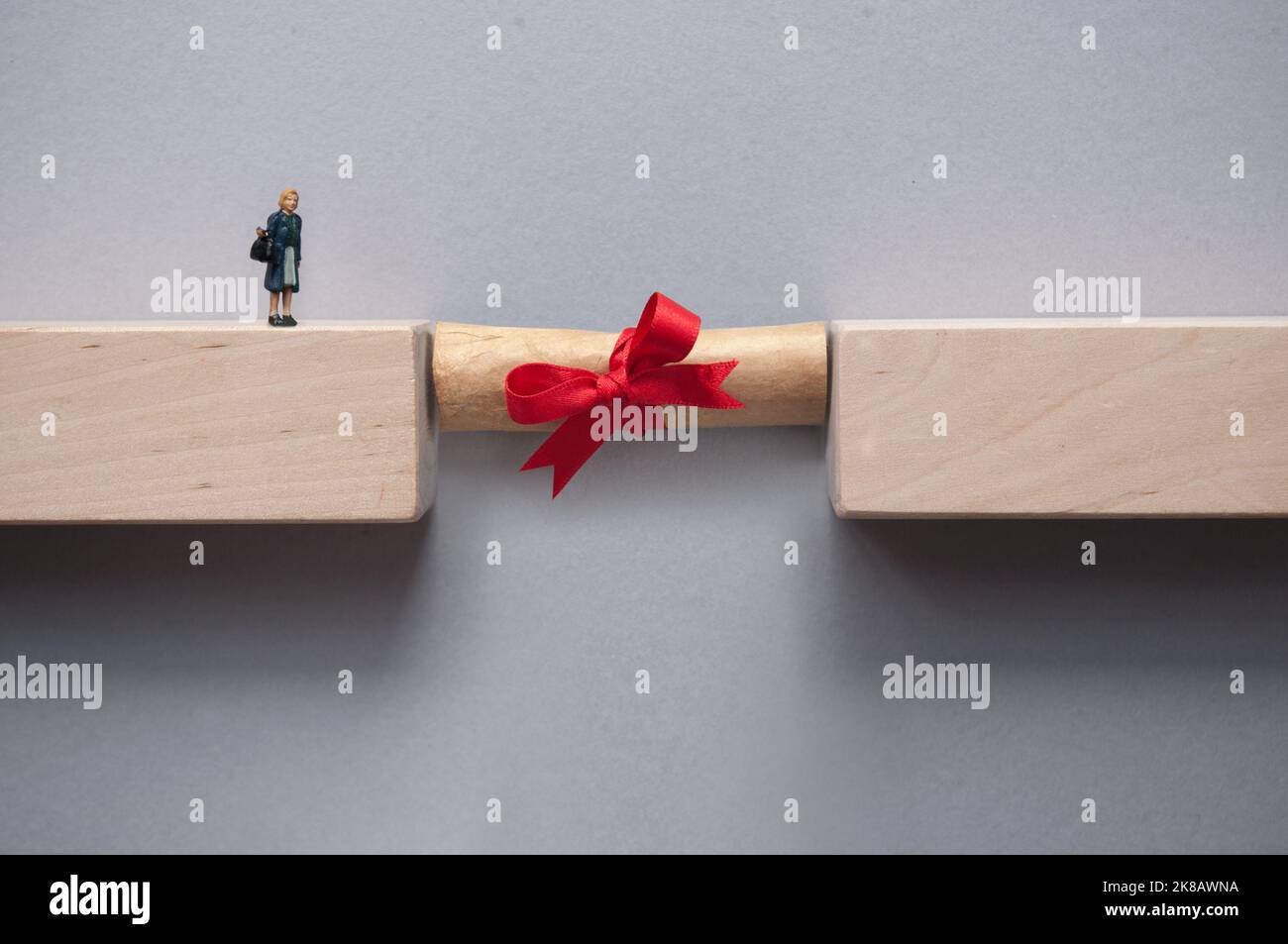 La scala graduata colma lo spazio tra i blocchi di legno per far incrociare la figura miniaturizzata femmina Foto Stock