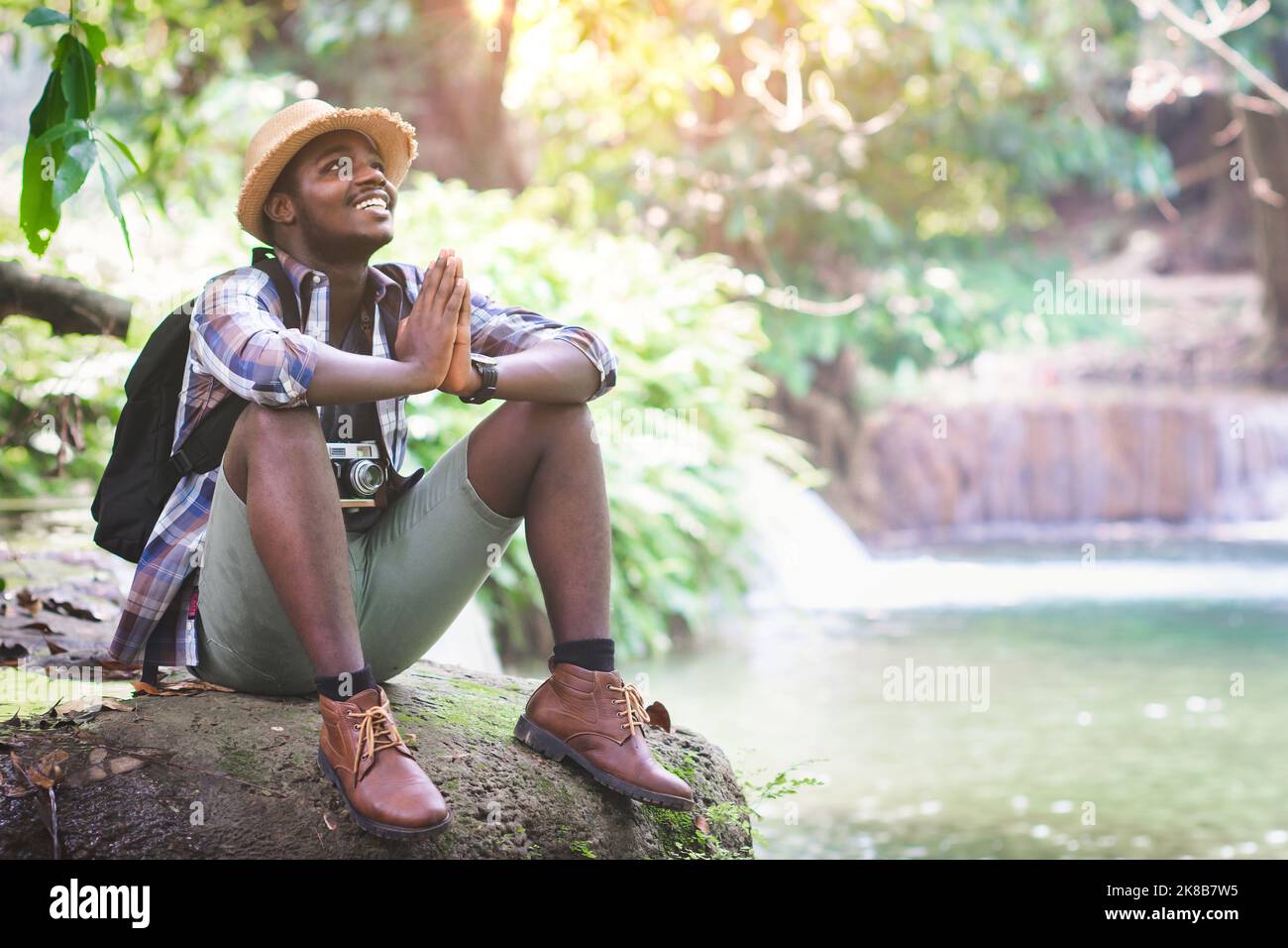Il turista africano del trekking prega di ringraziare Dio per le cose buone nella sua vita. Concetto di fede, religione e buona vita. Foto Stock