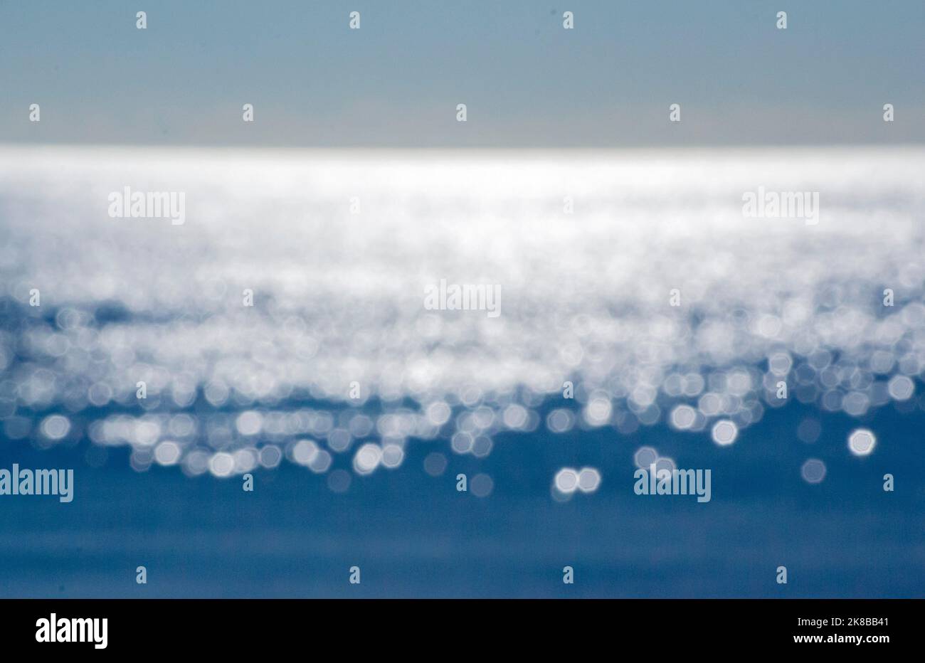 Astratto sfondo sfocato.spot di riflessi bianchi di sole splendente sulla superficie blu di onde marine.Mare in giorno di sole.naturale sfocato bokeh texture sfondo.seamless looping.beautiful sfondo naturale Foto Stock