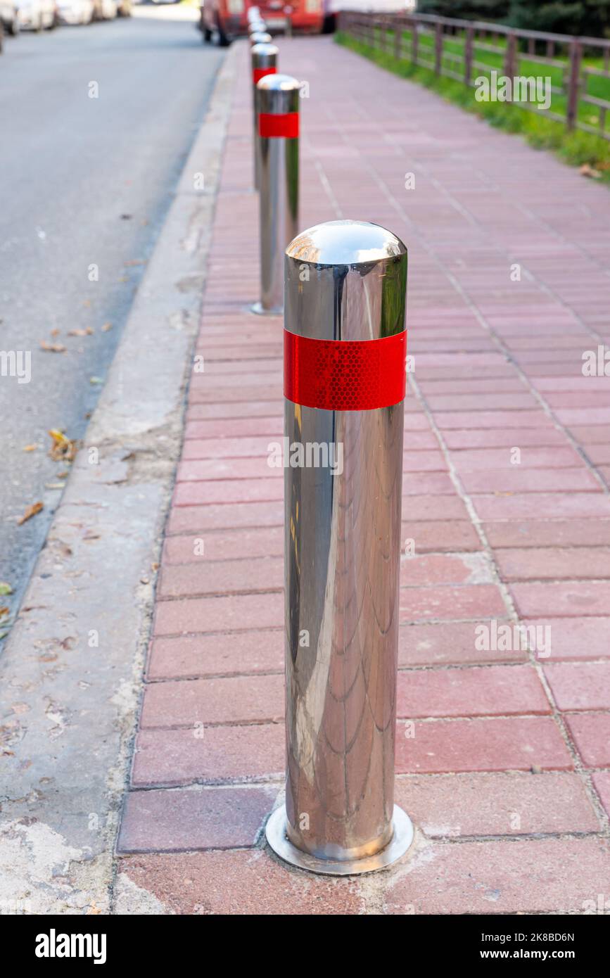 Pali di parcheggio in acciaio inossidabile che separano il marciapiede dalla strada. Prevenzione. Illegale. Controllo. Urbano. Città. Parcheggio non disponibile. Sentiero Foto Stock
