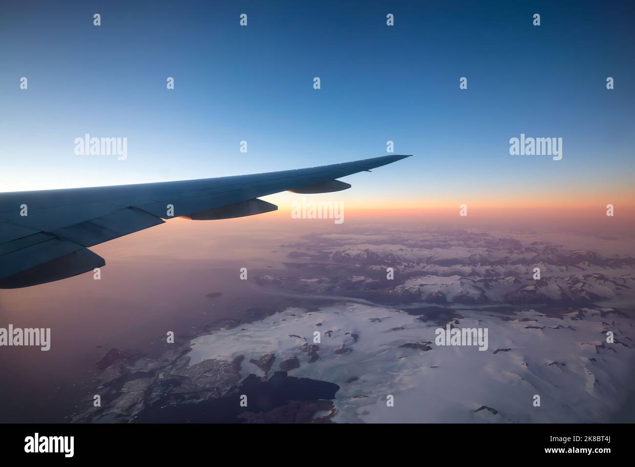Aviazione commerciale Jetplane volare sopra il paesaggio di montagna di ghiaccio sulla costa oceanica della Groenlandia. Foto Stock