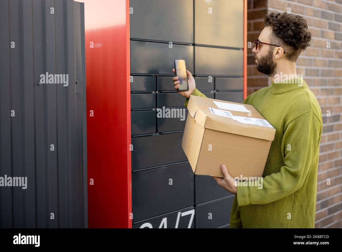 Uomo che riceve il pacco dalla cassetta postale automatica Foto Stock