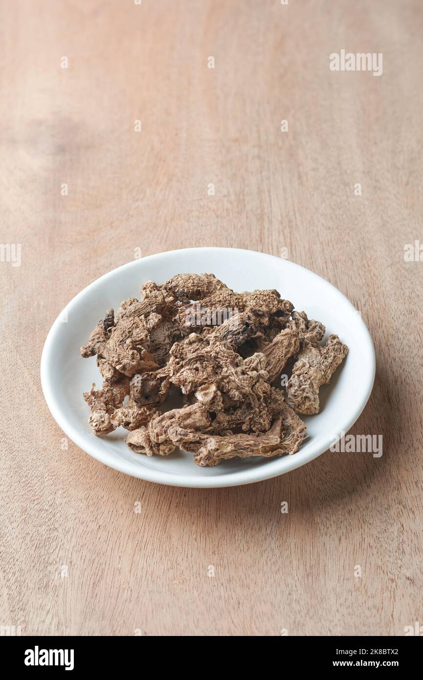 zenzero essiccato al sole su un piatto bianco, aromatizzante e ingrediente di erbe con forti benefici per la salute su un tavolo in legno, preso con spazio copia Foto Stock