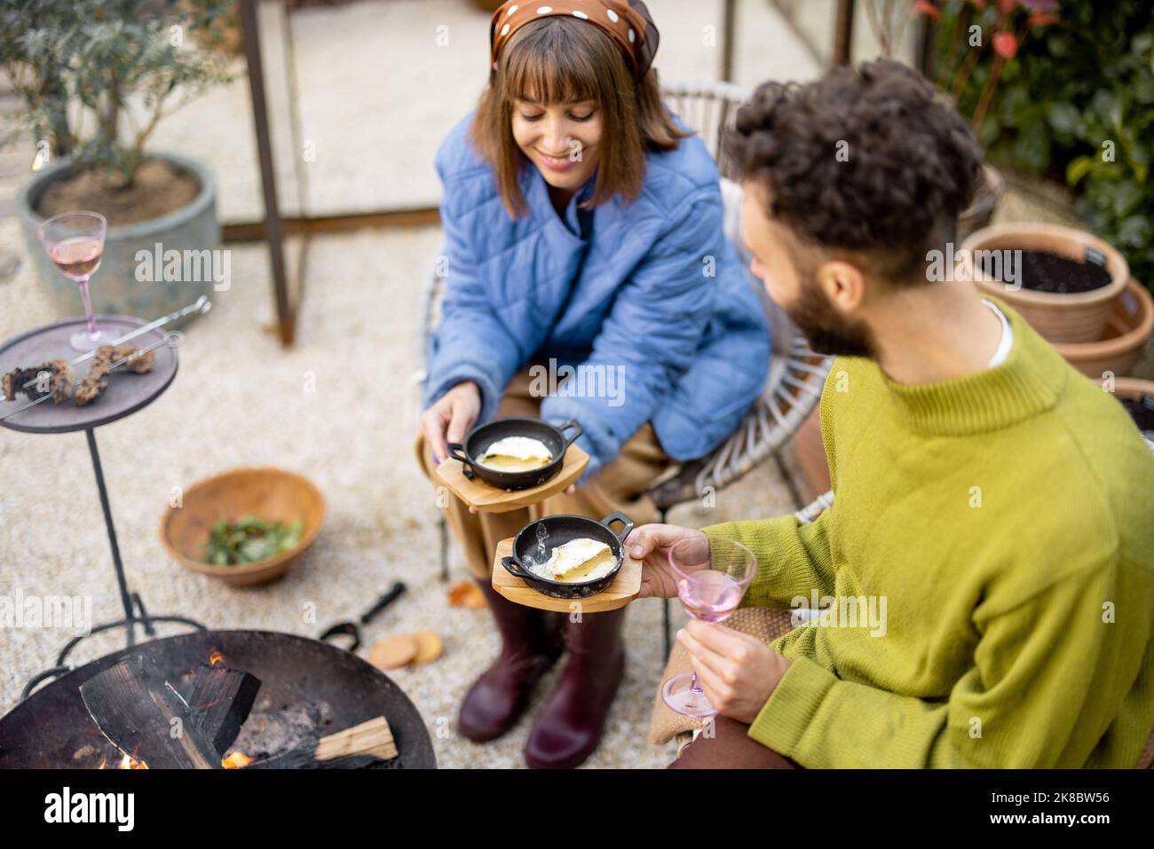 Uomo e donna hanno una cena accanto al fuoco all'aperto Foto Stock