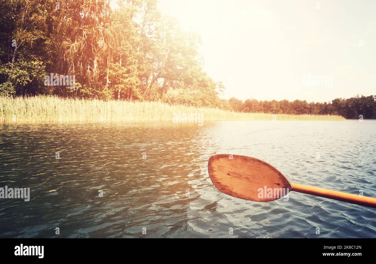 Immagine dai toni retrò di un vecchio kayak in legno pagaia sull'acqua del lago, fuoco selettivo. Foto Stock