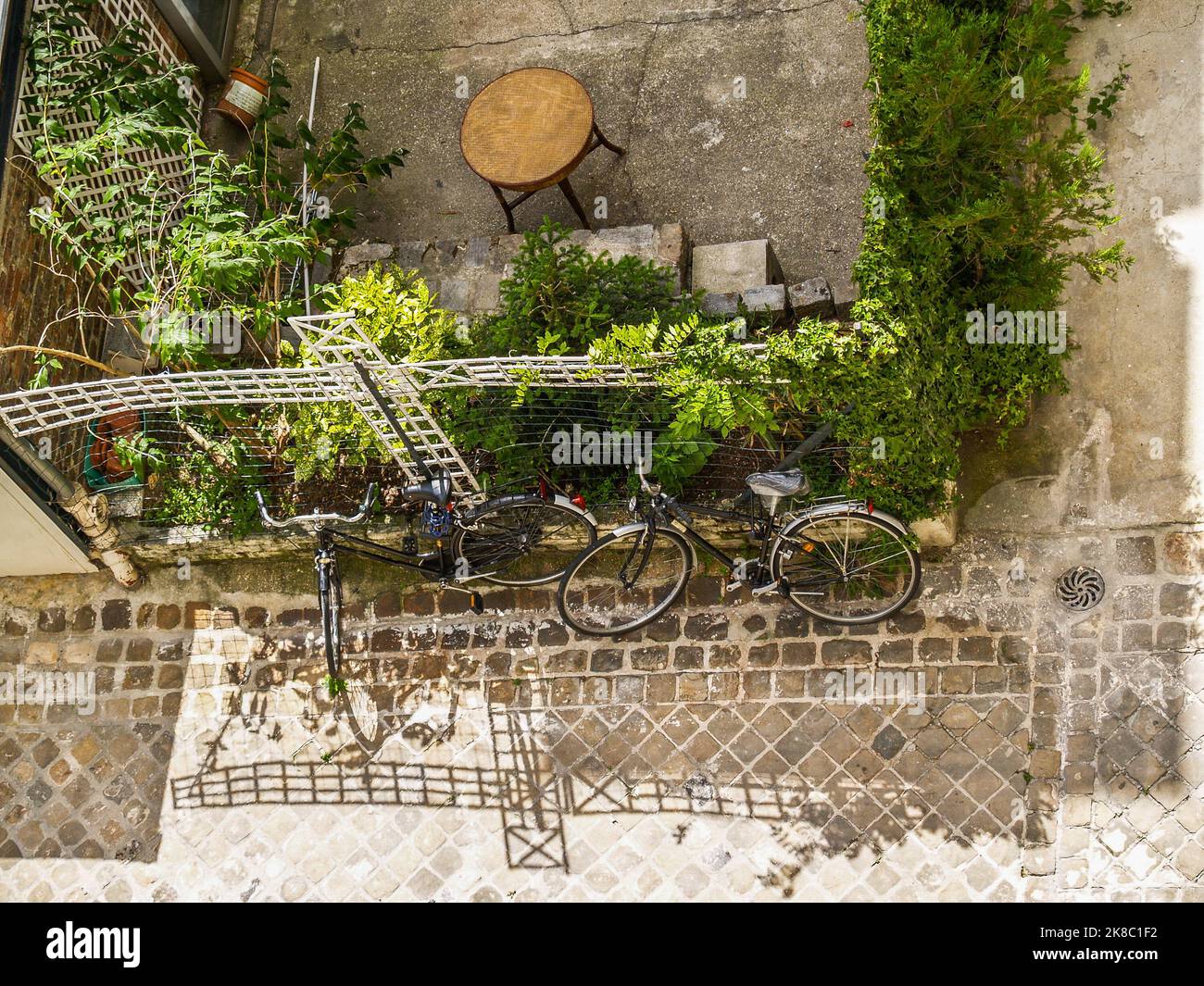 Vista alta del tipico cortile urbano europeo con due biciclette e recinzioni ombreggiate. Foto Stock